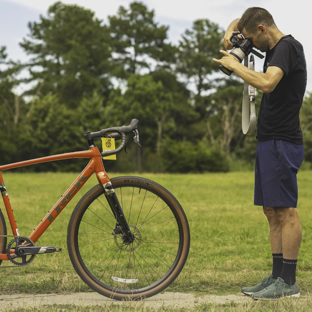 Photographer taking a photo of a Trek Checkpoint ALR 5 gravel bike in a grassy field